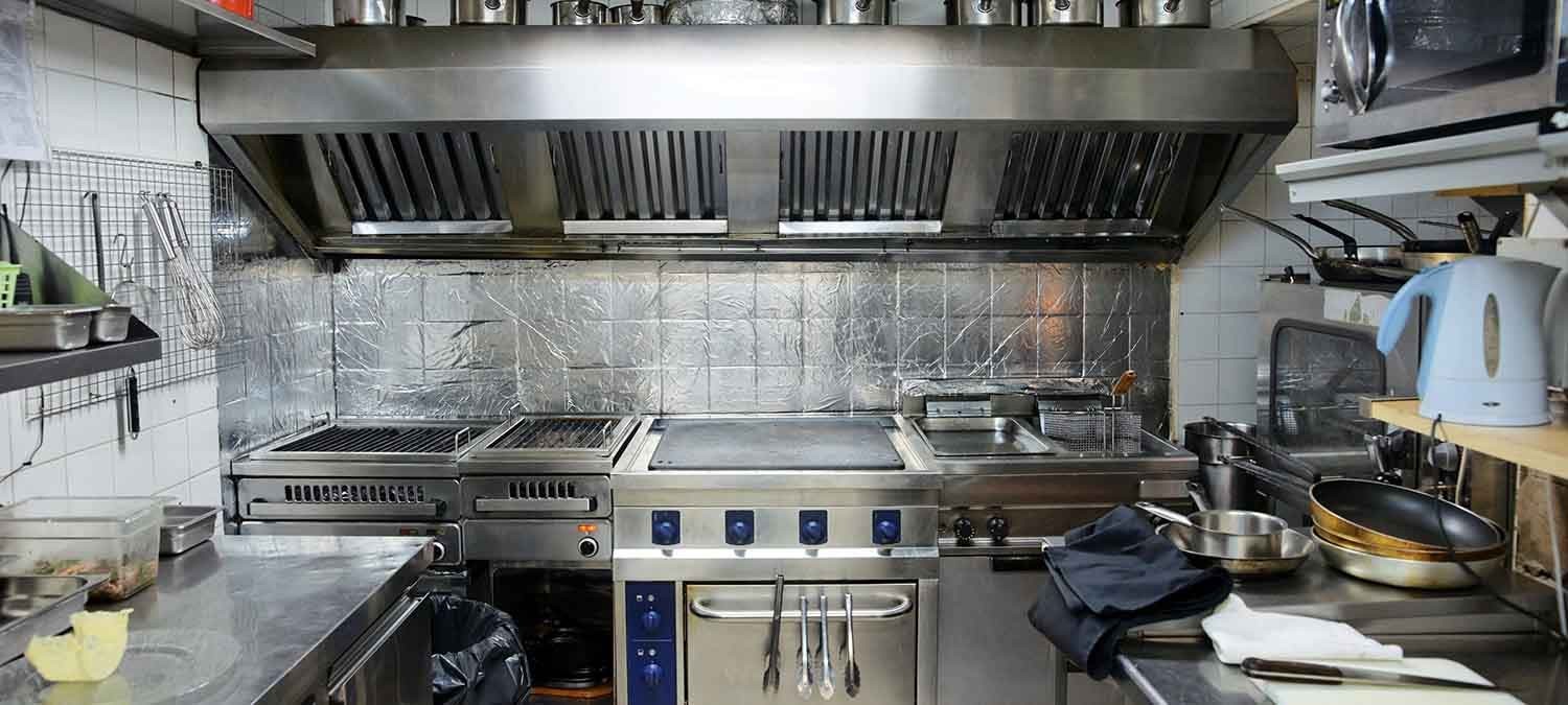Working commercial kitchen cooking line and stainless steel extraction hood with grease and carbon build-up
